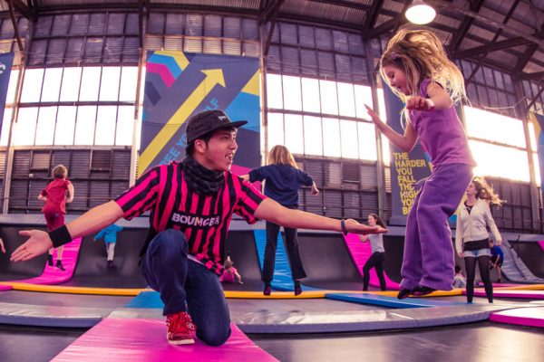 Photo of a staff member helping a girl jump